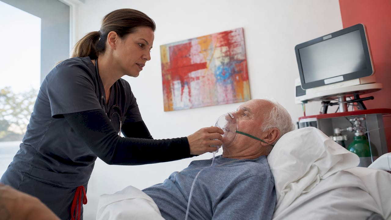 Respiratory therapist adjusting oxygen mask in hospital room