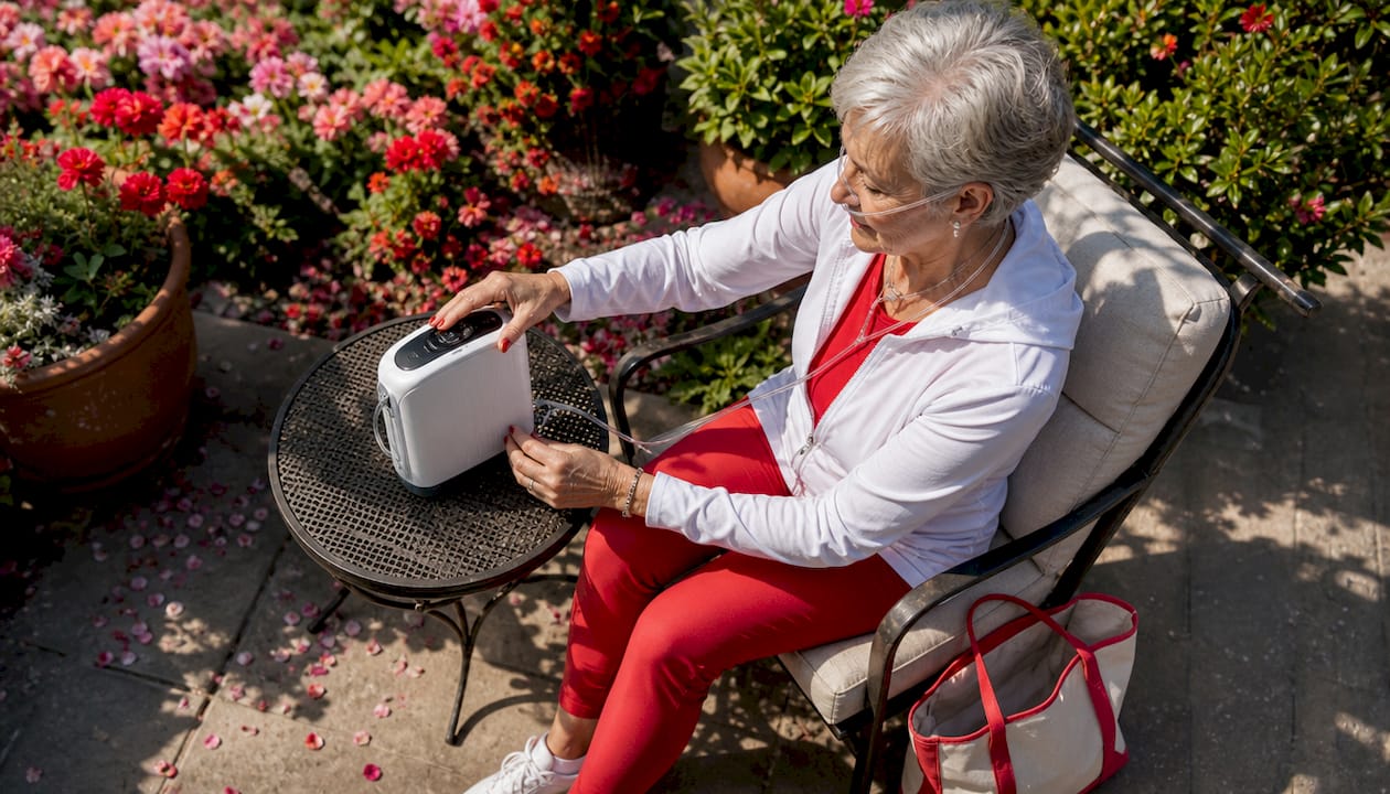 Senior woman adjusting portable oxygen concentrator outdoors