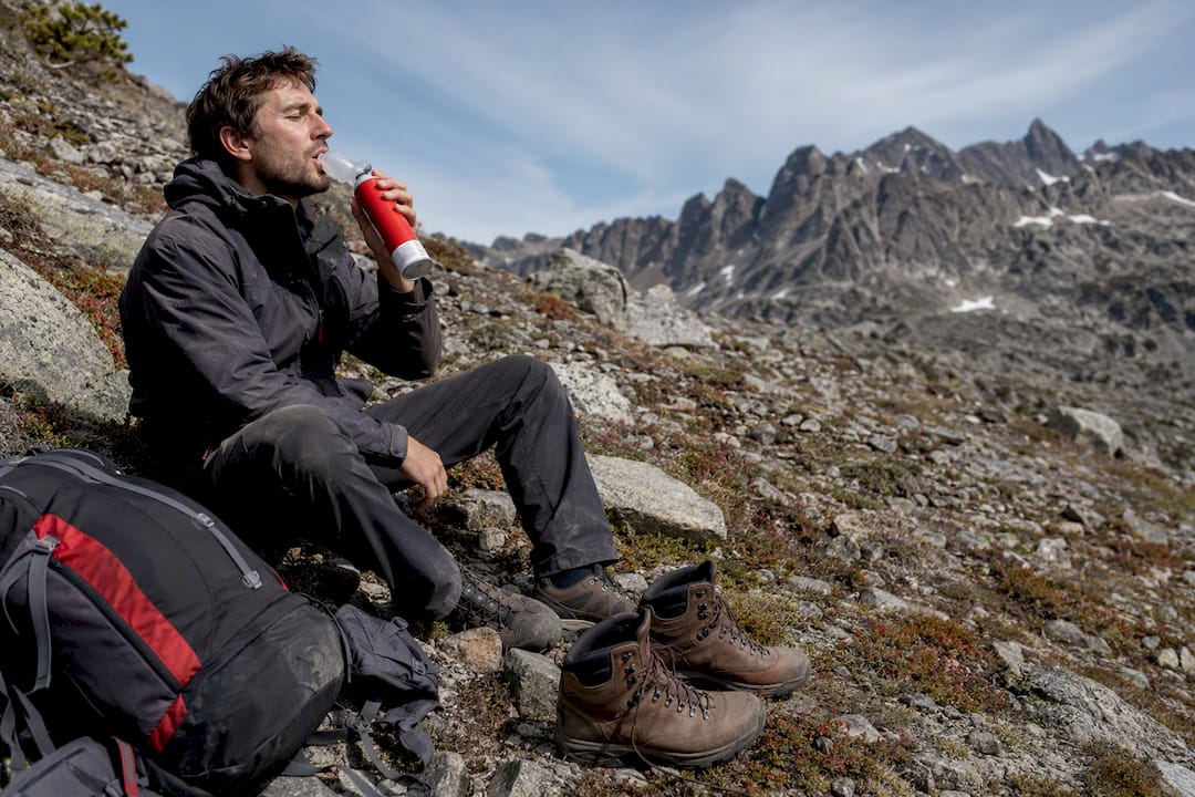 Hiker using canned oxygen on mountain trail