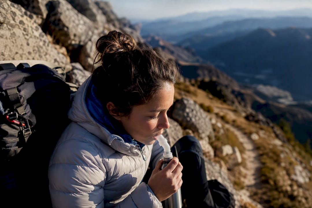 Hiker using canned oxygen on mountain trail
