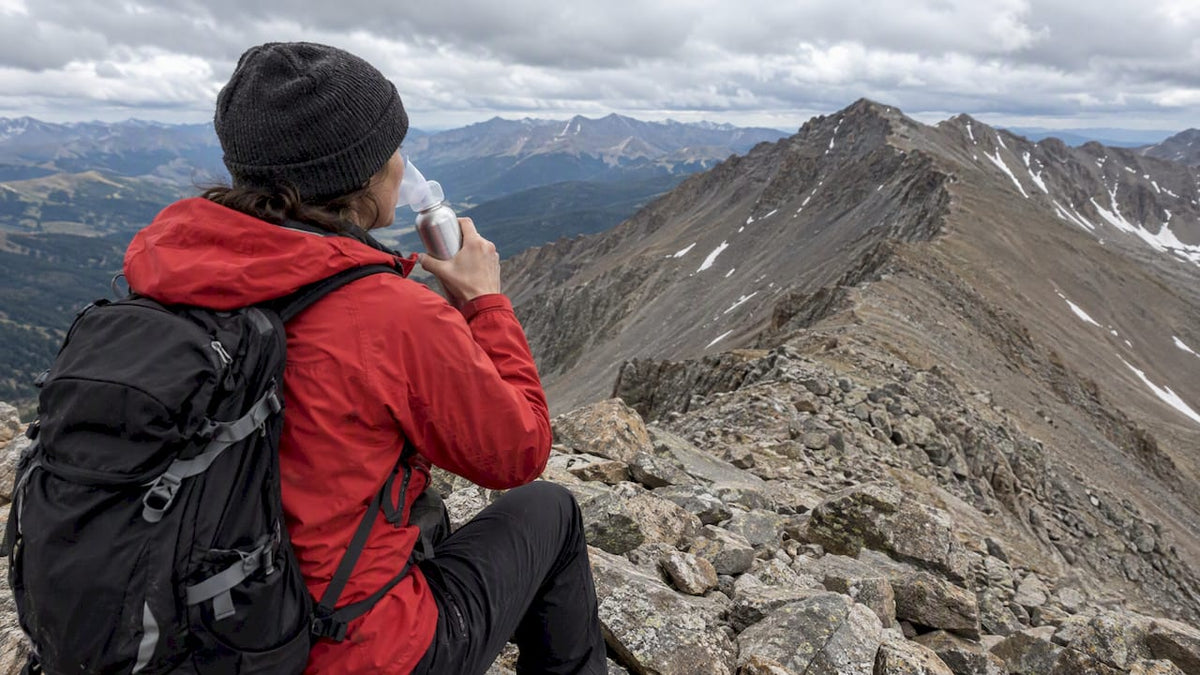 Hiker using portable oxygen on a mountain ridge